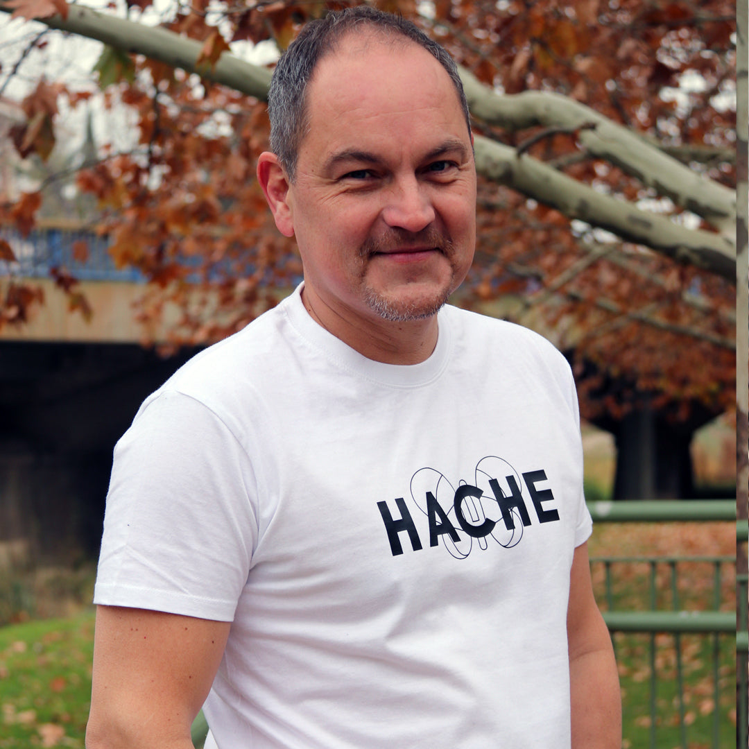 chico con camiseta blanca de manga corta con silueta de mariposa negra central y palabra HACHE superpuesta a la mariposa