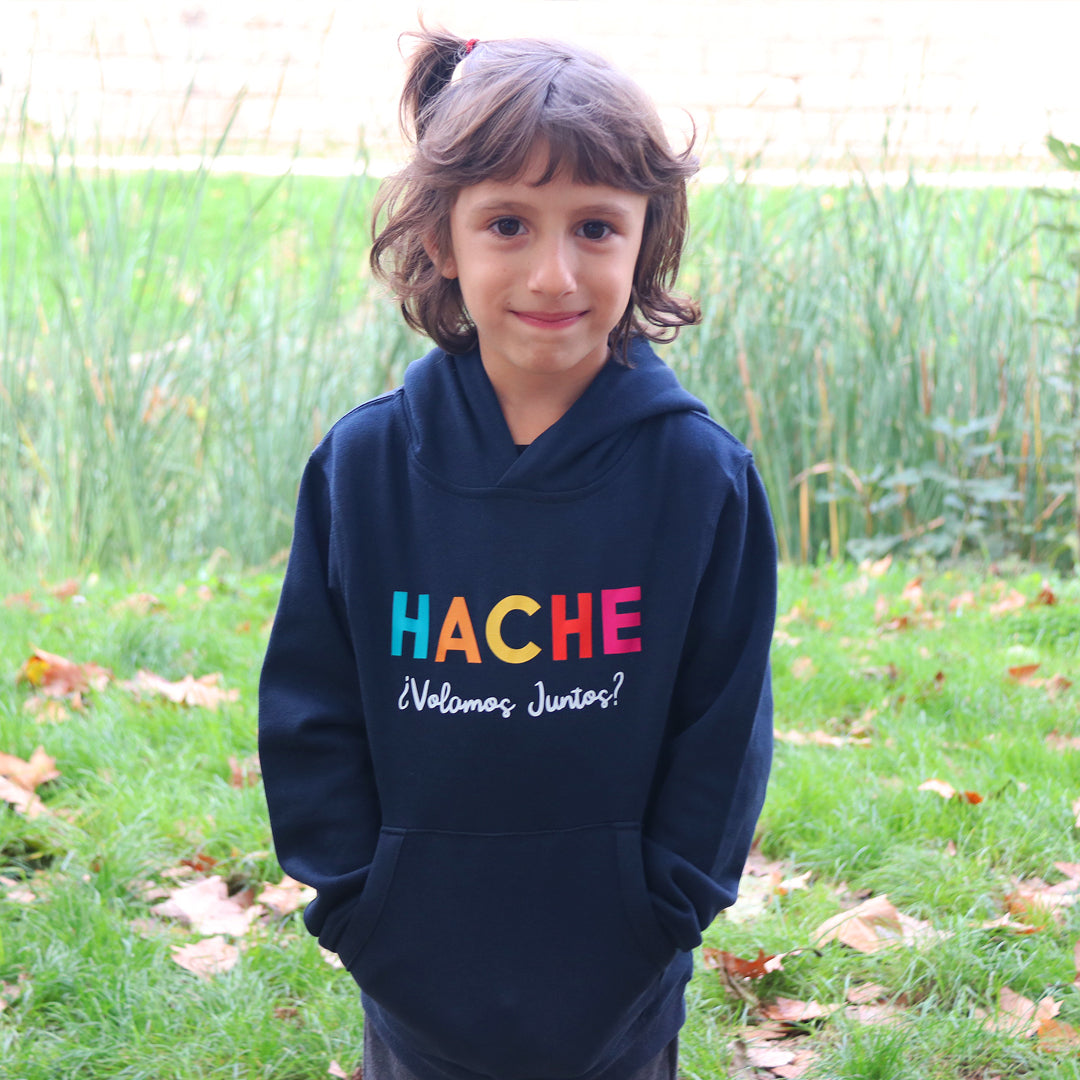Niña con sudadera azul y letras HACHE multicolor