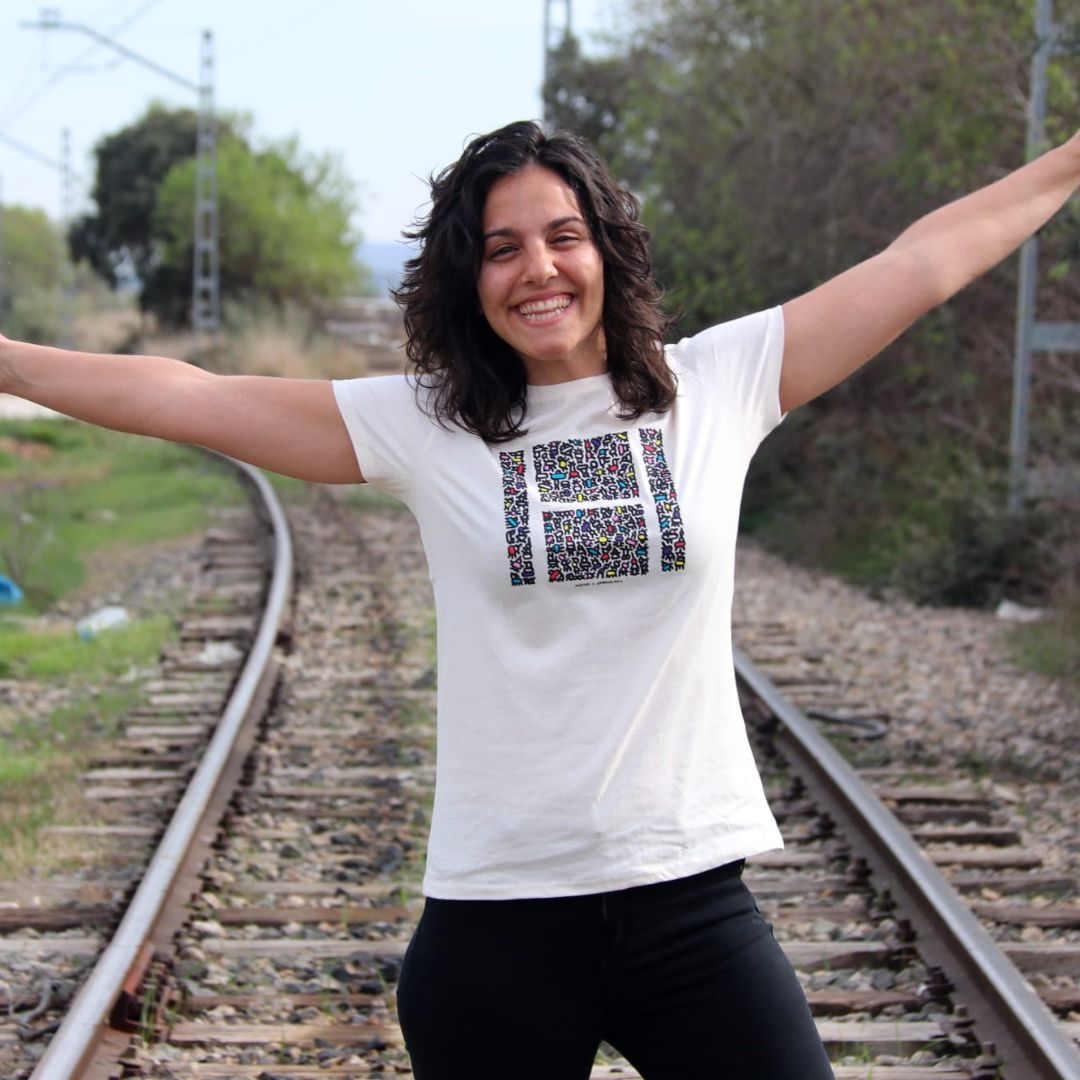 Chica sonriendo en primer plano posa con la camiseta abriendo los brazos hacia arriba