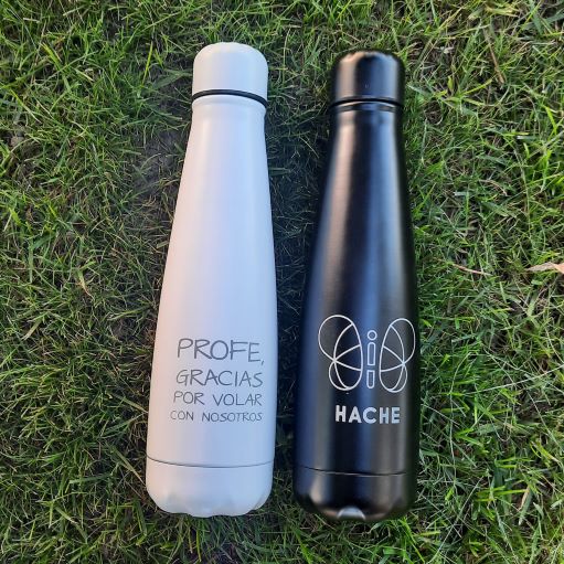 Botella negra con logo HACHE en silueta blanca y botella blanca con frase "profe, gracias por volar con nosotros"