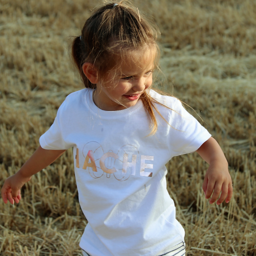 Niña con camiseta blanca con palabra HACHE escrita en rosa plateado y silueta de mariposa detrás.