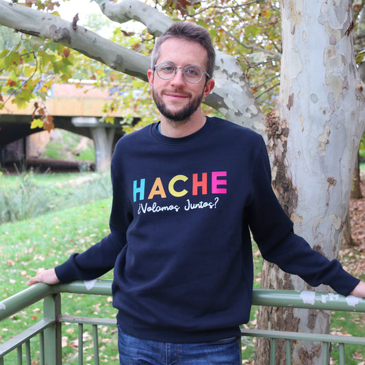 Chico con sudadera azul marino posando delante de un árbol