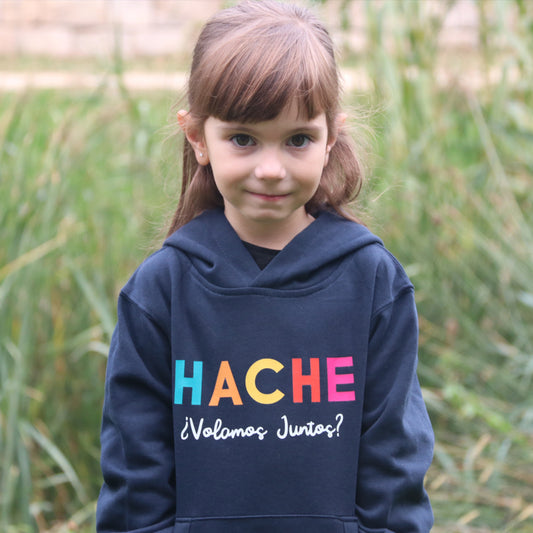 Niña con sudadera azul y letras HACHE en multicolor