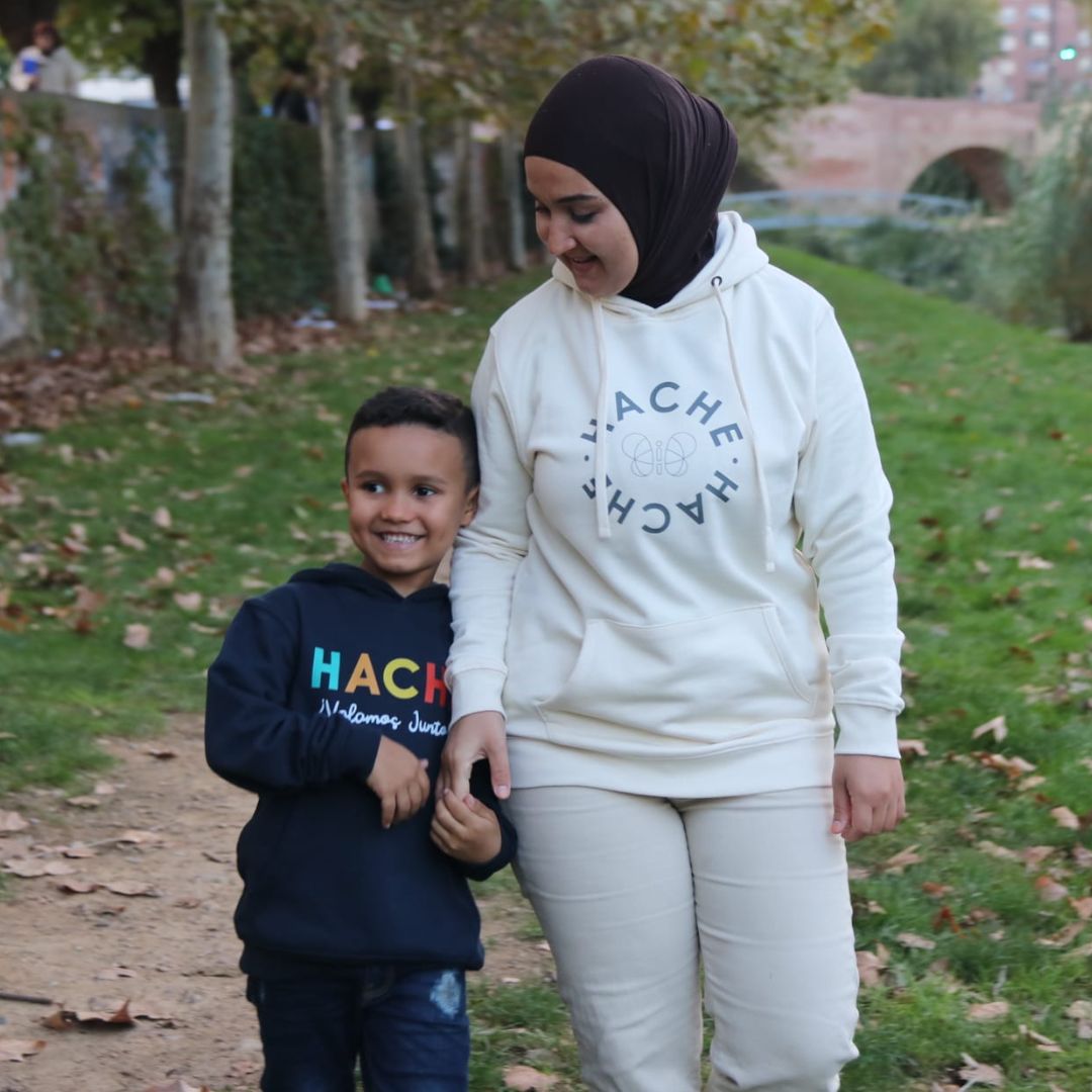 Niño y madre pasean de la mano con sudaderas Hache