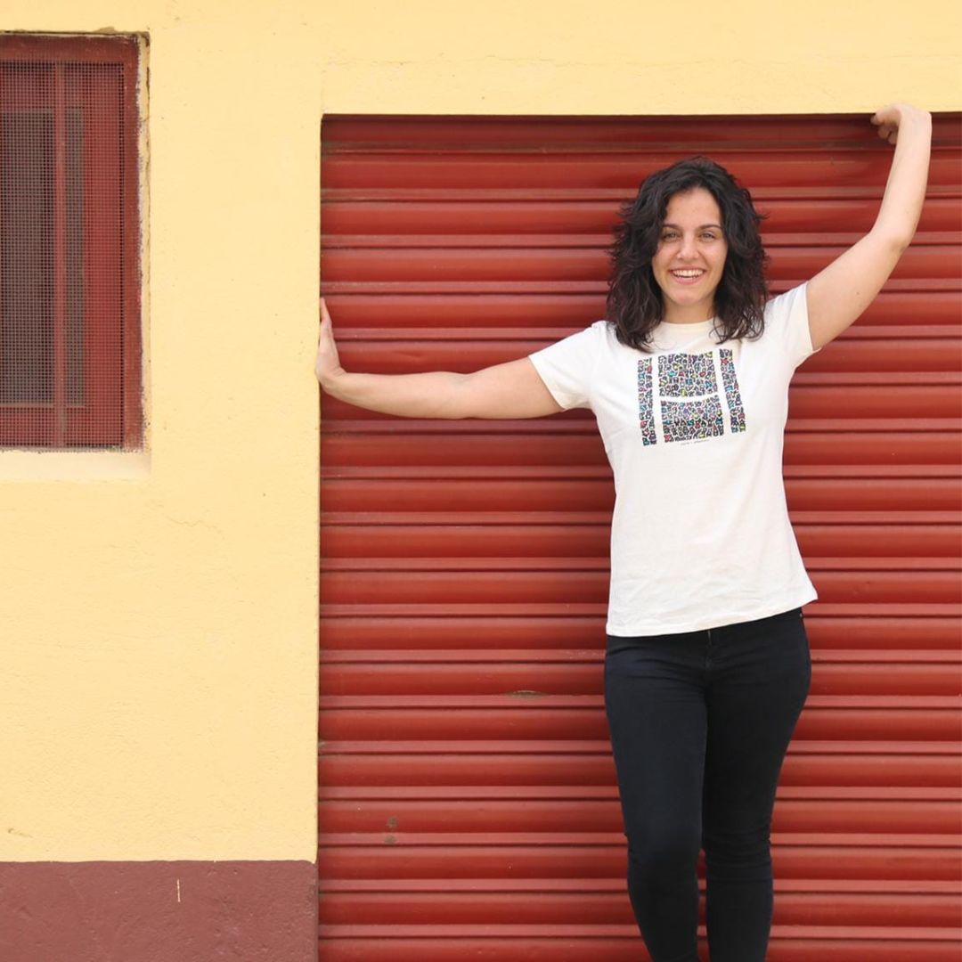 Chica con camiseta del producto se apoya en el marco de un garaje granate